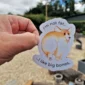 A lady's hand holding a sticker featuring an illustration of a plump Corgi dog with the text 'I'm not fat - I like big bones...'